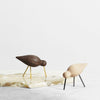 "Brown and beige wooden bird figurines on a marble surface, featuring sleek designs and gold and black accents."