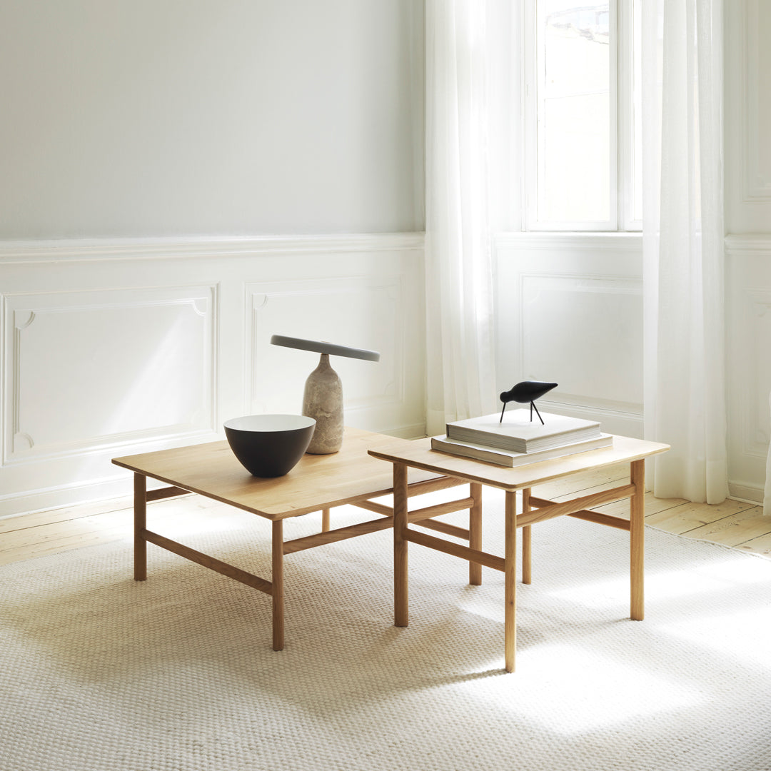 "Light wood coffee tables with a minimalist design, set against a soft neutral backdrop and bright natural lighting."
