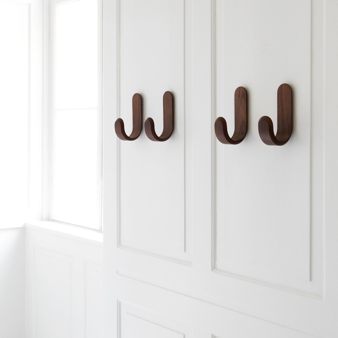 Brown wooden hooks on a sleek white wall, showcasing a modern and minimalistic design.