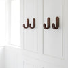 Brown wooden hooks on a sleek white wall, showcasing a modern and minimalistic design.