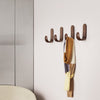 Brown wall hooks with a scarf featuring a geometric pattern in yellow, beige, and purple draped elegantly.