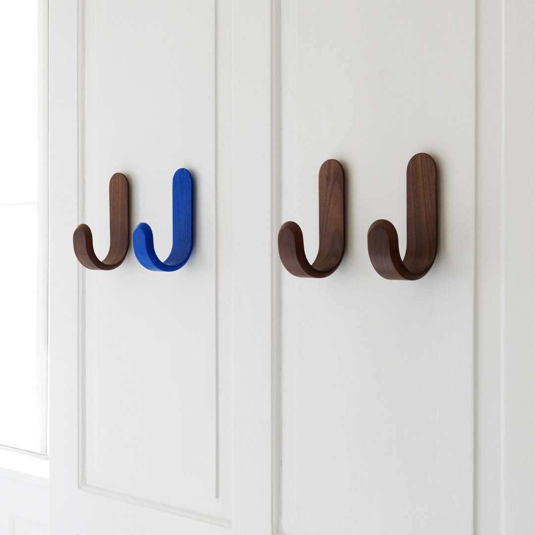 "Wooden wall hooks in brown and blue, showcasing sleek curves and modern design against a white backdrop."