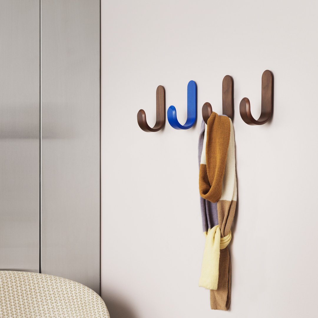 Colorful wall hooks in blue and brown, with a stylish scarf in warm, muted tones hanging from them.