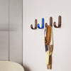 Colorful wall hooks in blue and brown, with a stylish scarf in warm, muted tones hanging from them.