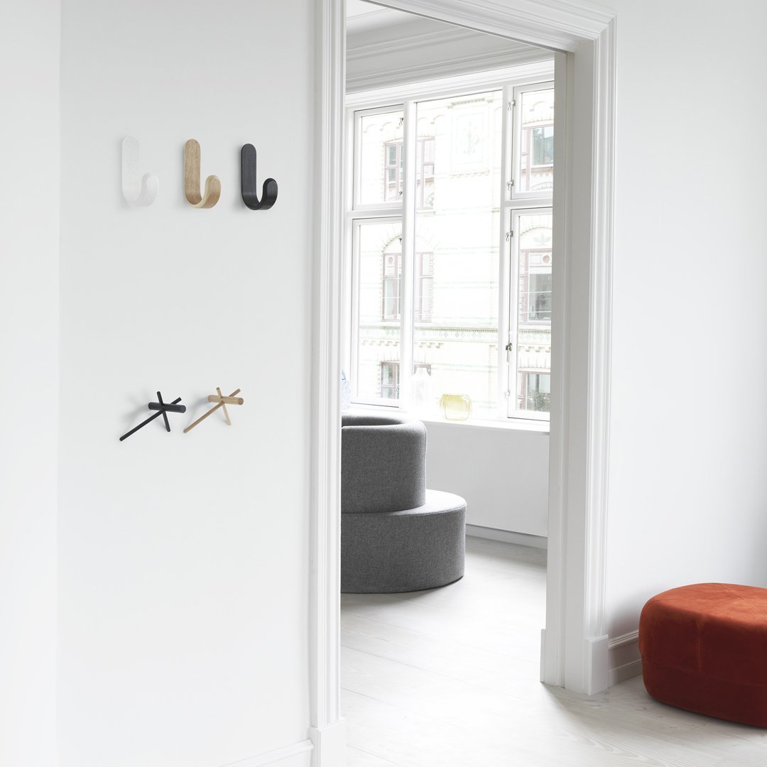 Colorful wall hooks in white, beige, black, and brass, complementing a minimalistic interior. Modern design with soft curves.