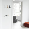 Colorful wall hooks in white, beige, black, and brass, complementing a minimalistic interior. Modern design with soft curves.