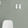 Two minimalist white wall hooks on a soft green background, highlighting simplicity and modern design.