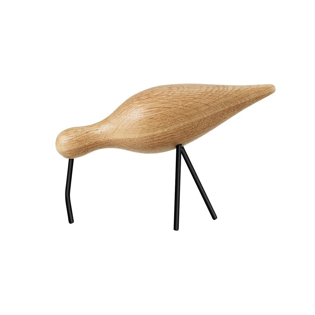 Wooden bird figurine with a smooth, natural oak finish and sleek black metal legs. Minimalist design in earthy tones.