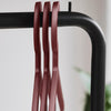 Red metallic hangers on a black rack against a soft, light background, creating a modern, minimalistic aesthetic.