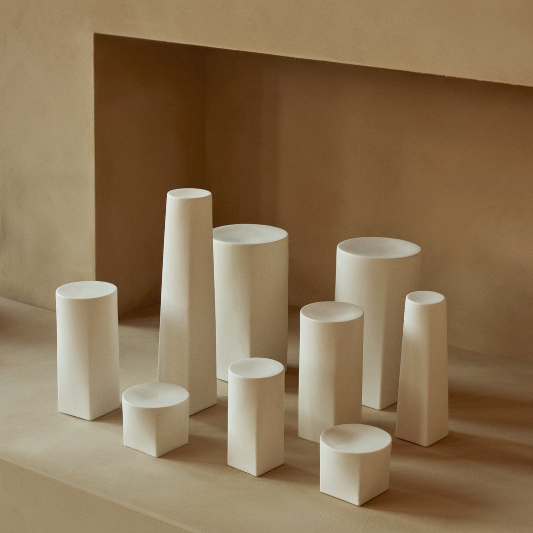Set of neutral-colored ceramic vases in various geometric shapes, showcasing soft white and beige tones.