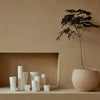 "Collection of matte white vases with varied shapes against a warm beige background."