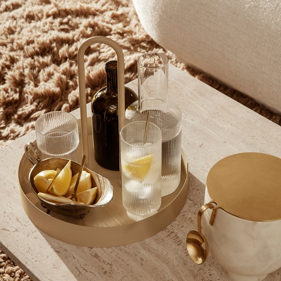 Elegant gold serving tray with minimalist design, featuring clear glassware and patterned lemons. Ideal for stylish gatherings.