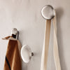 Sleek silver wall hooks with contrasting brown and cream fabric hanging, showcasing minimalist design and modern aesthetics.