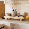 Natural wood shelf with neutral-toned containers and earthy decor, enhancing a minimalist aesthetic.