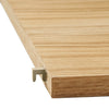 Light oak wood grain with subtle linear patterns and a hint of gold metal accent in the corner.