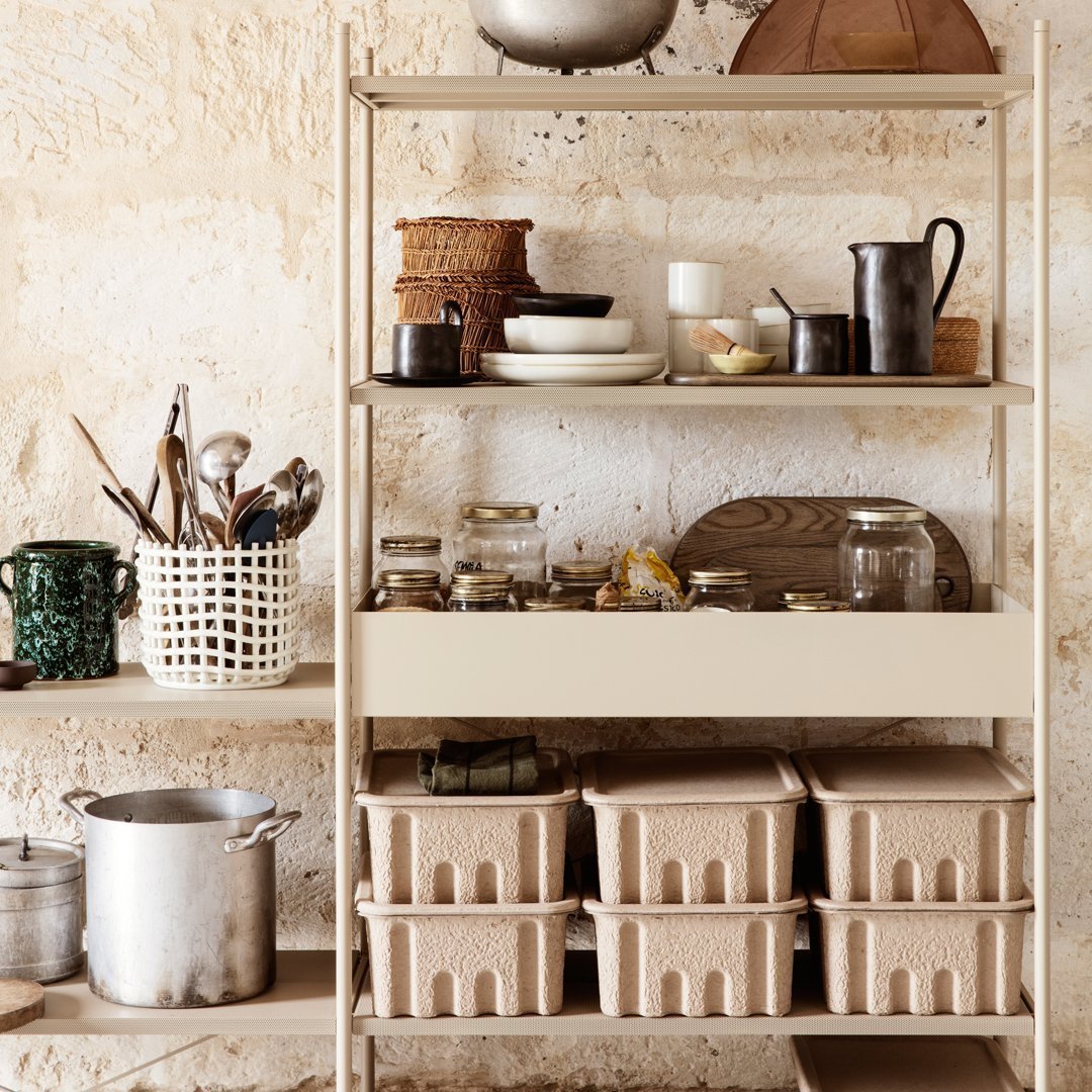"Neutral beige shelving with textured baskets, clear jars, and assorted kitchenware in earthy tones."