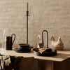 Elegant rustic dining setup with black plates, natural wood tones, and earthy textures against a neutral background.