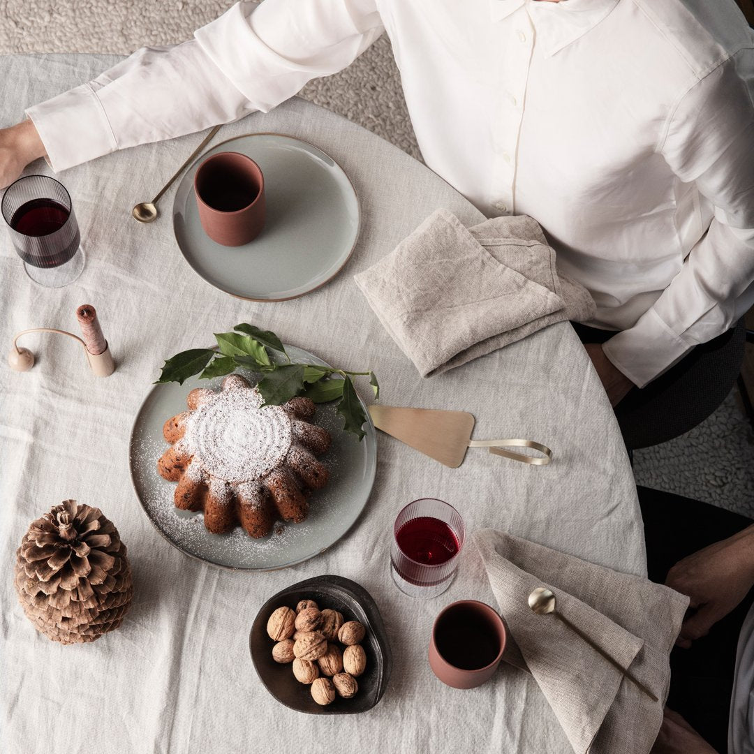 "Neutral table setting with earthy tones, textured napkins, and decorative patterns, featuring a circular cake centerpiece."
