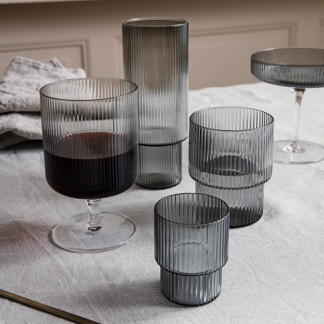 Set of ribbed glassware in smoky gray tones, featuring various shapes and sizes. Elegant, modern design for any table.