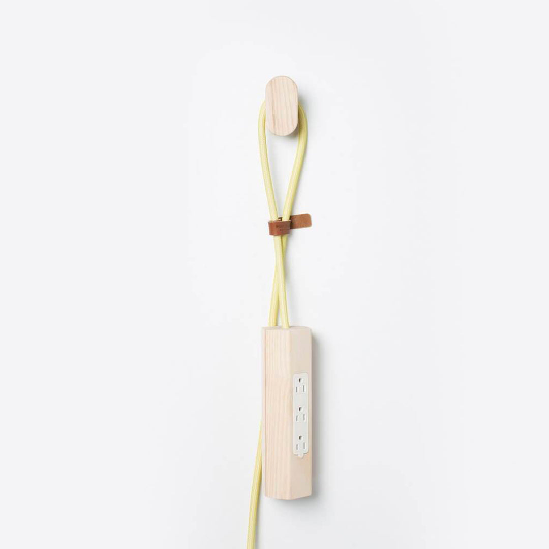 Wooden cord organizer with light yellow cord and brown leather accent against a clean white background.