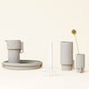 Soft gray ceramic set with minimalist shapes and a smooth matte finish, featuring a candle holder and vase.