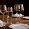 Elegant glassware set featuring clear and tinted glasses on a wooden table with white plates and napkins.