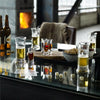 Beer glasses in clear glass featuring light gold and rich amber drinks, set against a reflective table and rustic background.