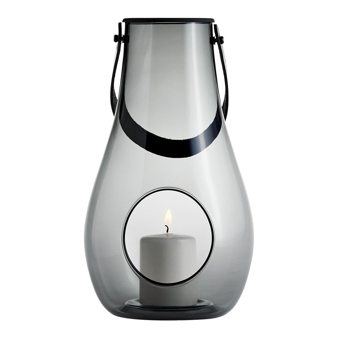 Smoke-gray glass lantern with a sleek black handle, showcasing a white candle inside a circular cutout.