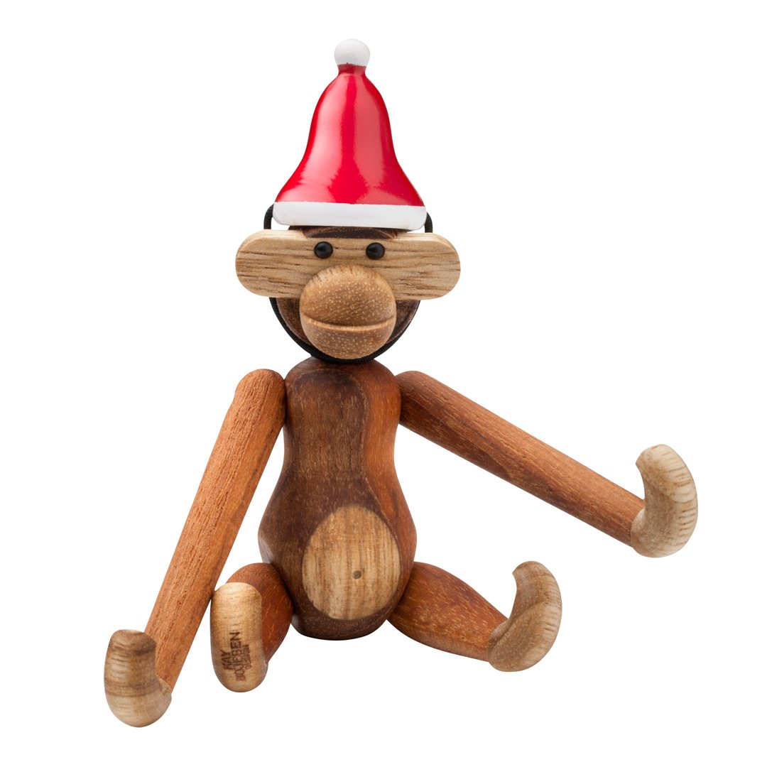 Wooden monkey figurine with a red Santa hat, featuring a mix of light and dark wood tones and smooth, polished surfaces.
