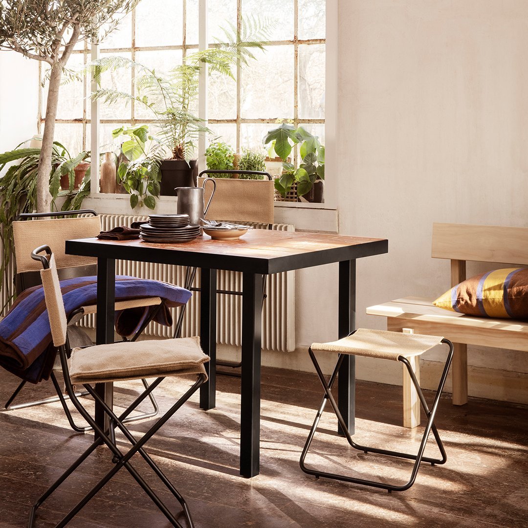 Modern black and wood table with natural-toned chairs, featuring colorful striped cushions and warm, inviting decor.