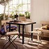 Modern black and wood table with natural-toned chairs, featuring colorful striped cushions and warm, inviting decor.